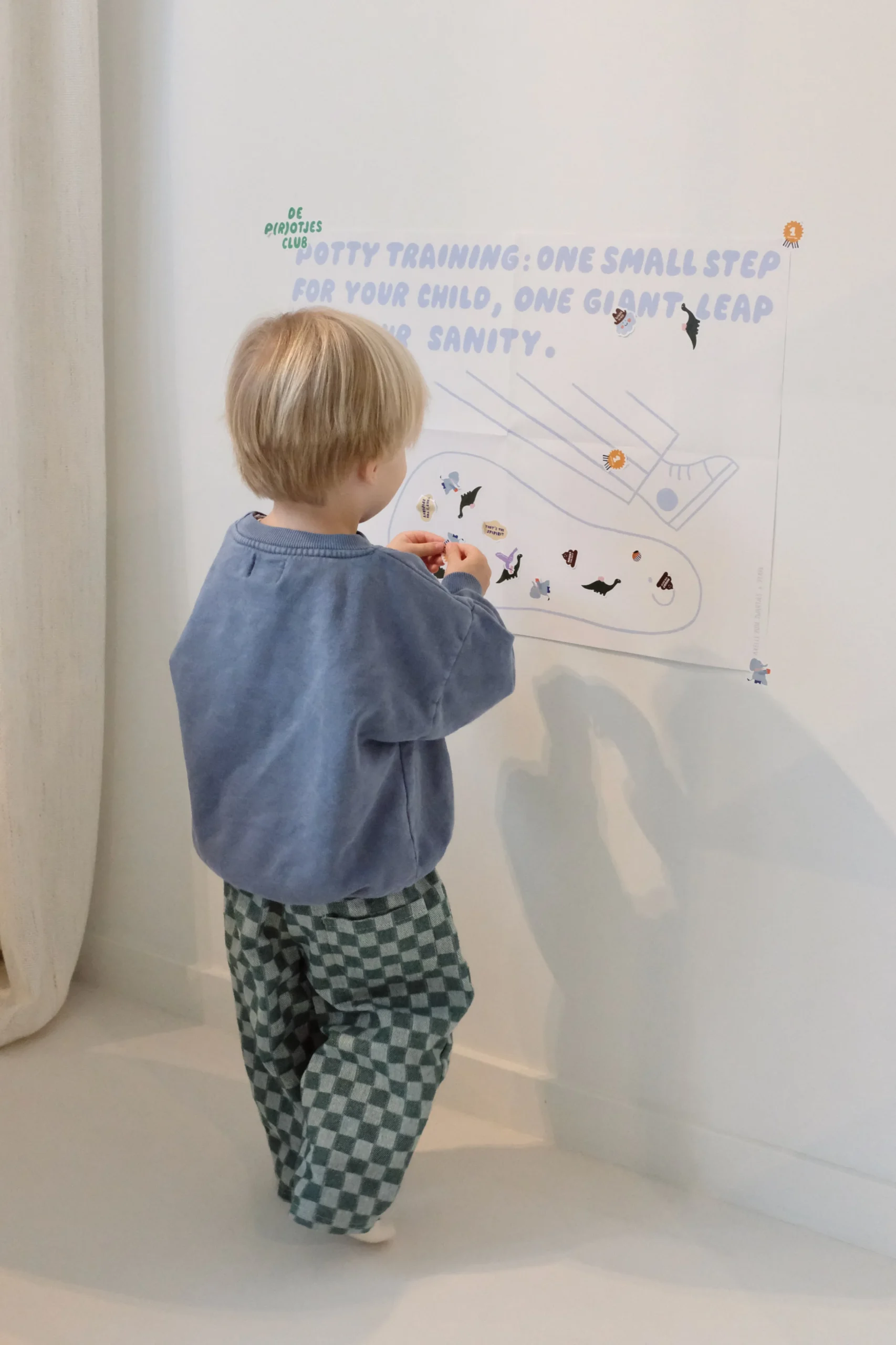 peuter bij een plaskalender aan de muur en een prentenboek over zindelijk worden